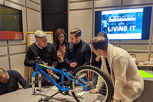Four corporate team building participants strategizing around a table while assembling a bicycle during a LEVEL 12 high-performance workshop.